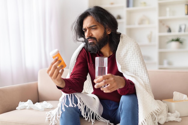 Un homme confus en regardant des médicaments à la maison.