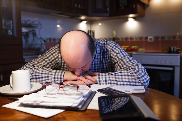 Un homme considère avec lassitude le budget familial Manque d'argent dans la crise