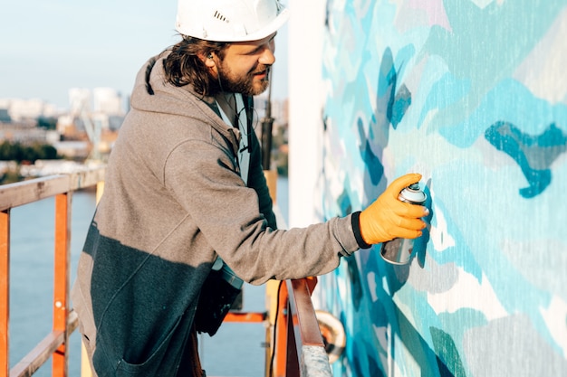 Homme constructeur peintre professionnel peint le mur d'un nouveau bâtiment