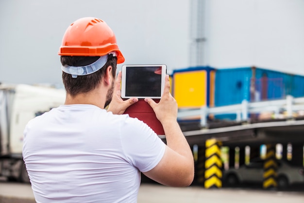 Homme de constructeur travaillant avec une tablette dans un casque de protection. Construction, sécurité, performance.