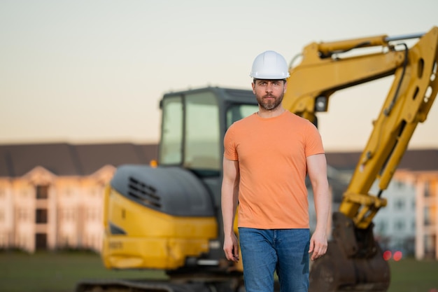 L'homme de la construction avec l'excavatrice au travailleur du site industriel dans la construction de casque avec l'ingénieur bulldozer wo