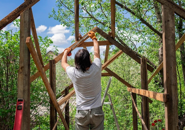 Homme construisant un toit en bois à l'aide d'un ruban à mesurer