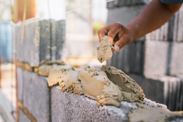 Un homme construit un mur avec un seau de ciment.