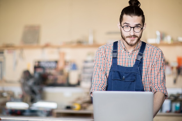 Homme contemporain utilisant un ordinateur portable en atelier