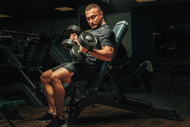 Homme avec corps de sport soulevant des haltères au gymnase