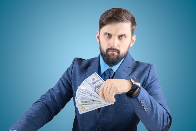 Un homme en costume d'affaires avec des billets dans ses mains semble droit, un homme d'affaires avec un fan d'argent regarde avec un regard tendu