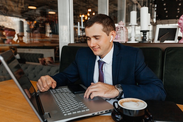 Un homme en costume d'affaires travaille sur un ordinateur portable dans un café. Homme d'affaires avec ordinateur portable.