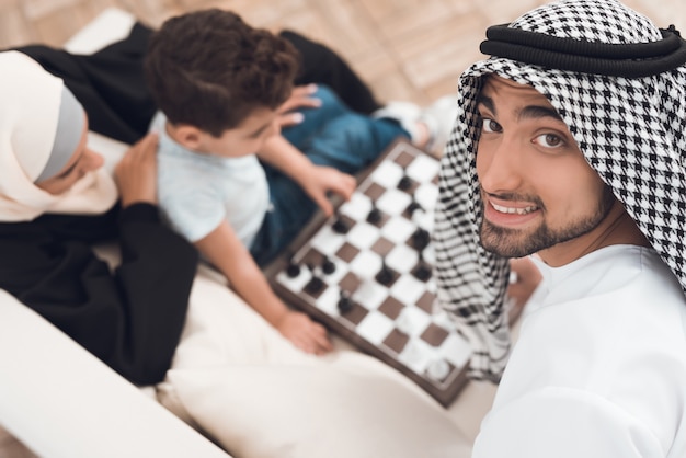 Un homme en costume arabe joue aux échecs avec un petit garçon.