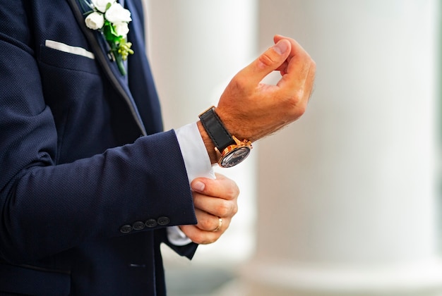 L'homme en costume bleu classique ajuste le bouton de manchette sur le revers de la chemise de la Saint-Valentin ou du mariage