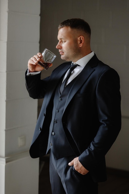 un homme en costume boit dans un verre