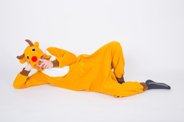 Homme en costume de cerf allongé sur le sol sur un mur blanc