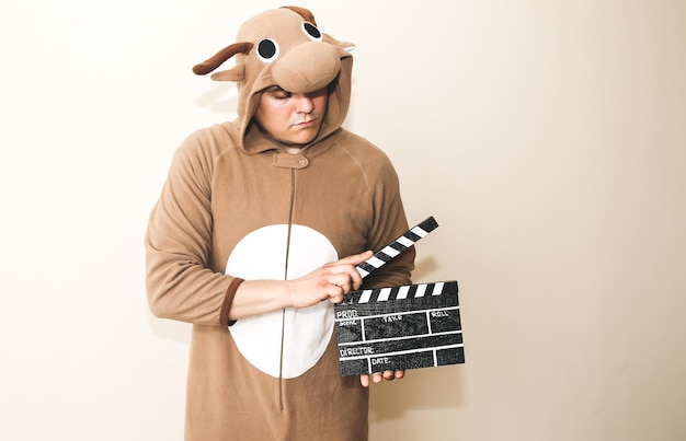 Homme en costume de cosplay tenant un clap noir. Guy dans les vêtements de nuit drôles de pyjamas d'animaux faisant un film. Réalisation et de film de cinéma amateur. Concept créatif. Anime japonais.