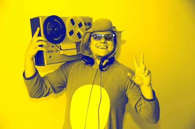 Homme En Costume Cosplay D'une Vache Avec Magnétophone à Bobines. Guy Dans Les Vêtements De Nuit Pyjama Animal. Photo Drôle Avec Des Idées De Fête. Musique Rétro Disco.