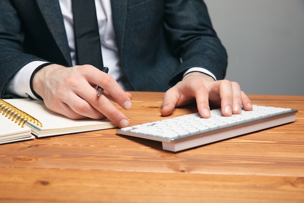 Un homme en costume écrit sur un clavier sur une surface grise