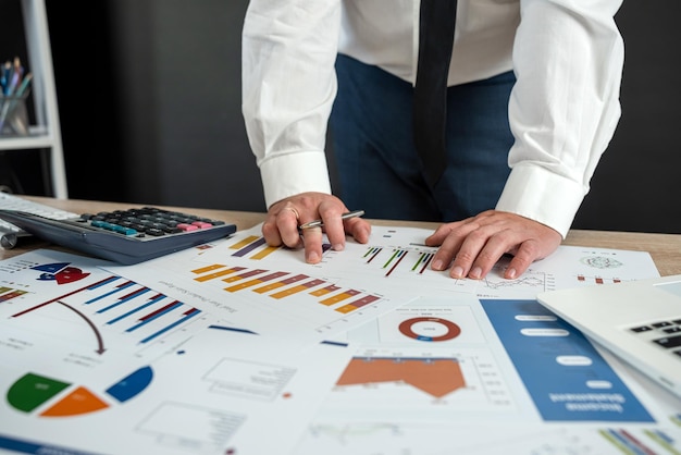 L'homme en costume fait l'analyse des données du rapport annuel les tableaux et les graphiques au bureau