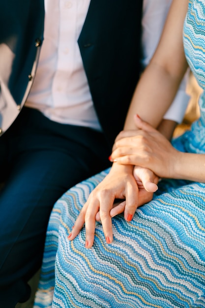 Homme en costume et femme dans une robe bleue rayée sont assis main dans la main