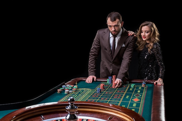 Un homme en costume avec une femme vêtue d'une belle robe noire jouant à la roulette au casino. Jeux d'argent. Casino. Roulette. Poker.