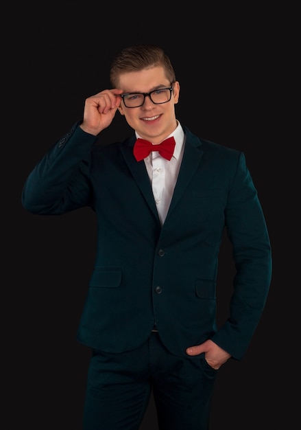 Homme en costume formel, noeud papillon rouge et lunettes pose