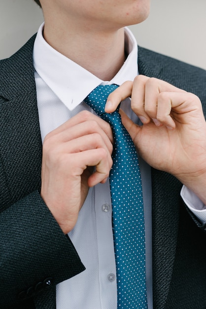 Un homme en costume gris et cravate bleue pose.