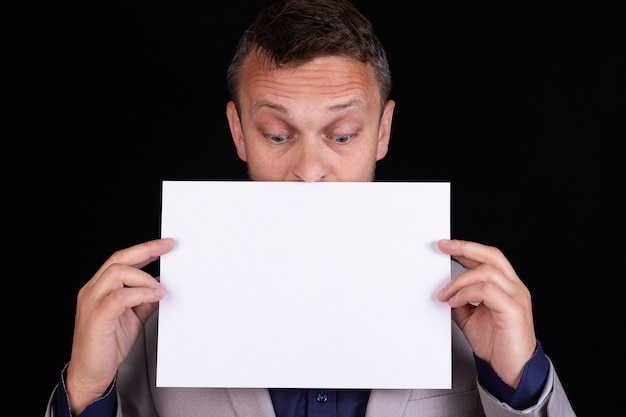 Un homme en costume gris tient une feuille de papier vierge