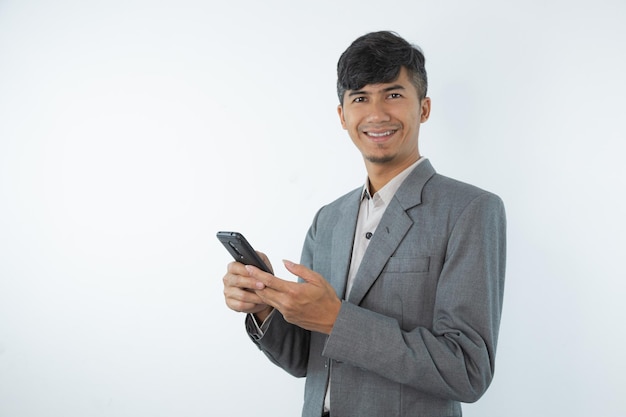 Un homme en costume gris tient un téléphone et sourit