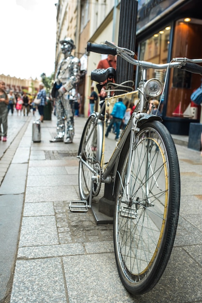 Un homme en costume de miroir avec une valise et un vélo appelle au magasin de Cracovie