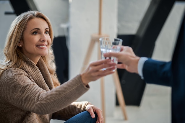 Homme en costume offrant un verre d'eau au client