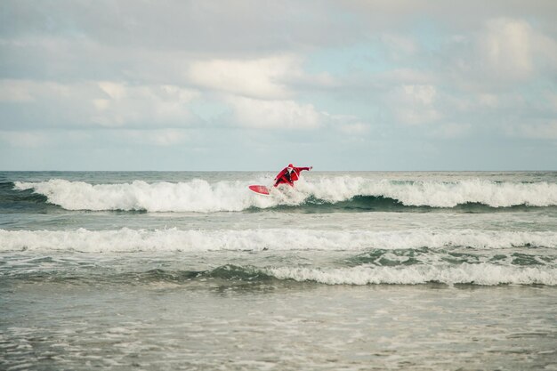 Photo un homme en costume de père noël surfe sur la mer contre le ciel