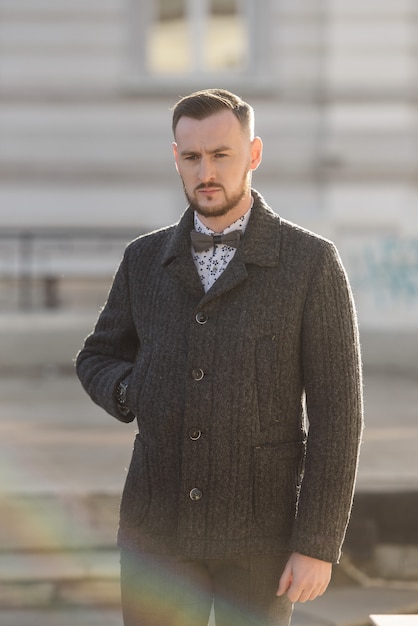 Homme en costume et pull pose dans la rue