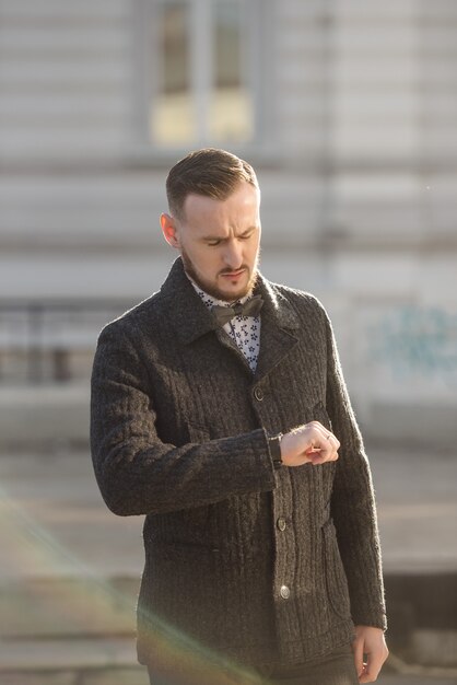 Homme en costume et pull pose dans la rue