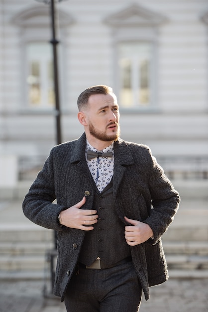 Homme en costume et pull pose dans la rue