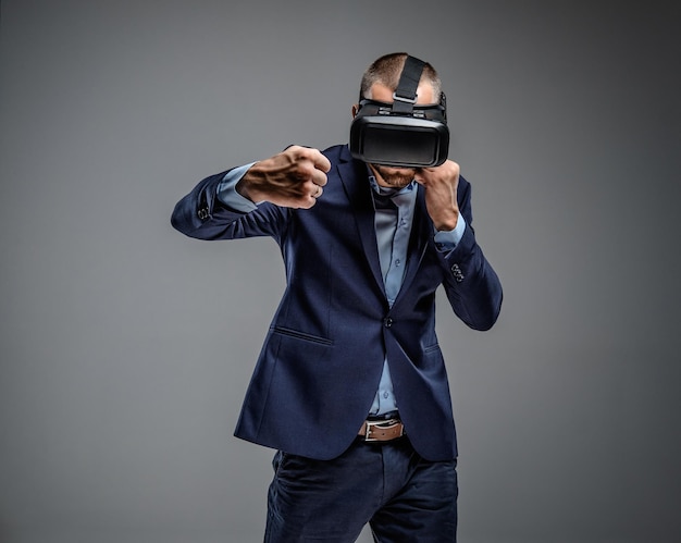 Homme en costume se battant avec des lunettes de réalité virtuelle sur la tête.