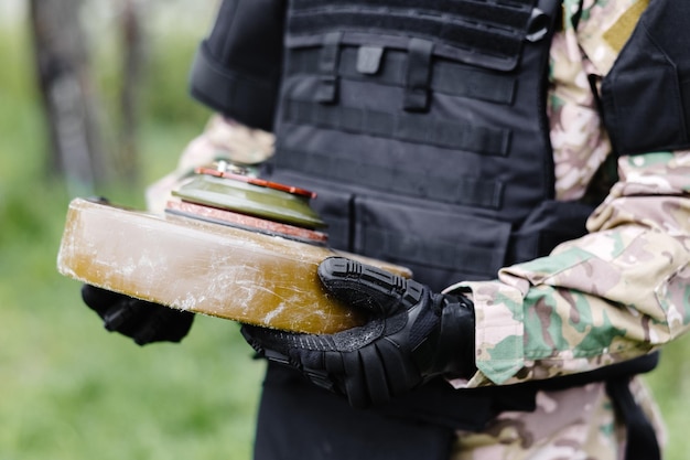 Un homme en costume spécial travaille avec un détecteur et a trouvé un engin explosif Un homme tente de neutraliser une mine antichar