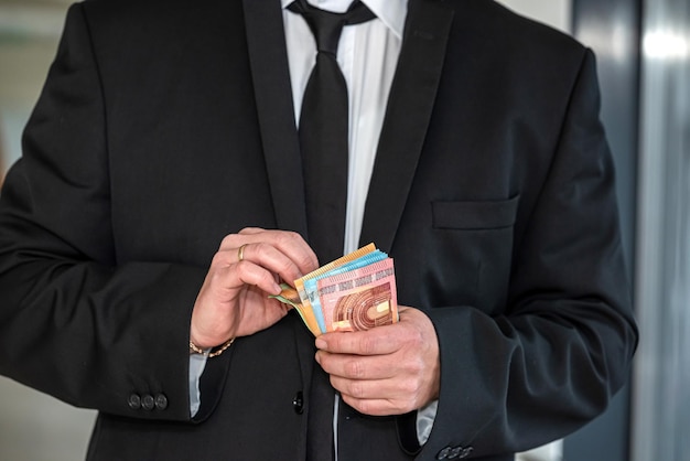 Homme en costume tenant des billets en euros au centre d'affaires Concept de paiement ou de don financier en espèces