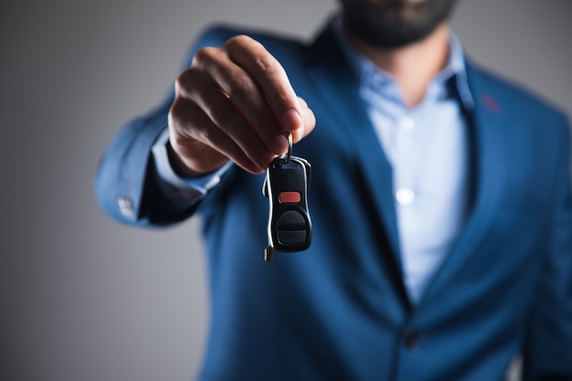 Un homme en costume tenant une clé de voiture