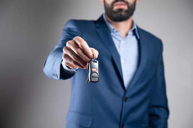 Un homme en costume tenant une clé de voiture