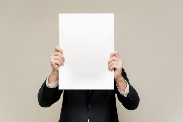 un homme en costume tient un drap blanc devant lui. homme se cachant derrière une affiche. l'homme sur le visage de l'espace de copie de motif blanc