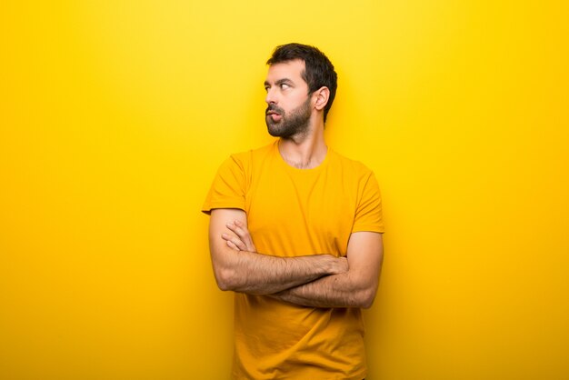 Homme de couleur jaune vibrante isolée avec une expression de visage confuse tandis que ses lèvres mordent