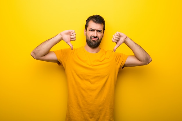 Homme de couleur jaune vibrante isolée montrant le pouce vers le bas avec les deux mains