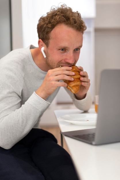 Homme de coup moyen mangeant un croissant