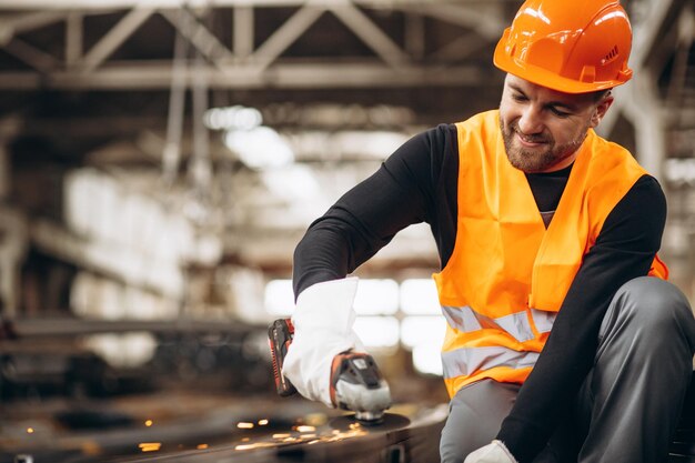 Homme coupant de l'acier à l'usine