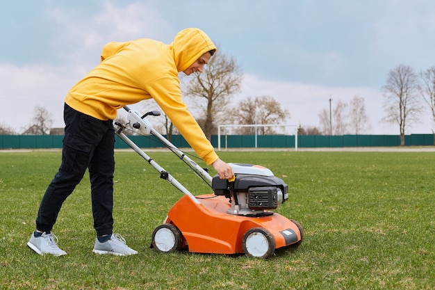 Homme coupant l'herbe verte avec tondeuse à gazon dans la cour