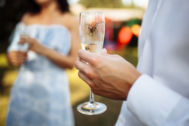 Un homme avec une coupe de champagne à la main sur une compagnie de gens en fête. Mariage, anniversaire, anniversaire.