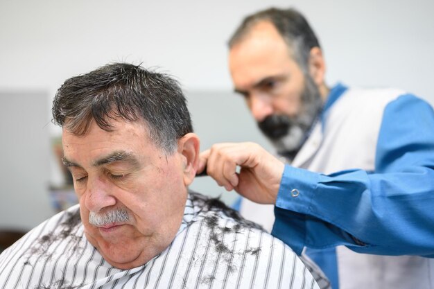 Photo un homme coupe les cheveux d'un client.