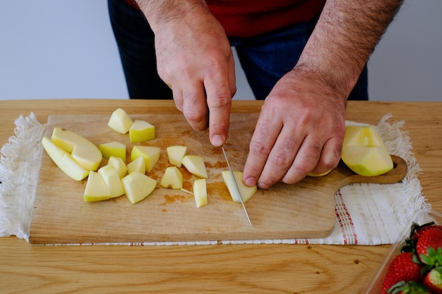 Photo un homme coupe une pomme sur une planche à couper en bois.