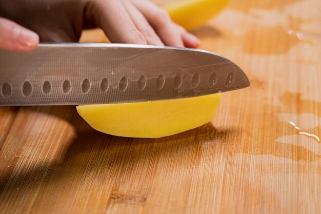 Photo un homme coupe une pomme de terre crue en préparant des légumes à la maison en cuisinant des aliments sains