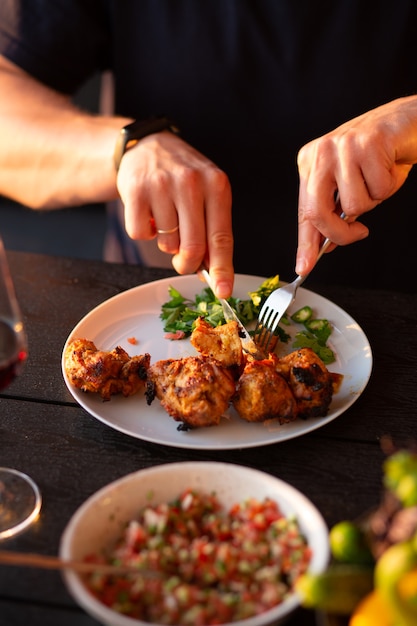 Un homme coupe de la viande avec un couteau, l'homme mange de la viande grillée au boeuf kebab salade de viande aux herbes