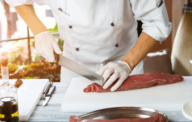 L'homme coupe la viande avec un couteau.