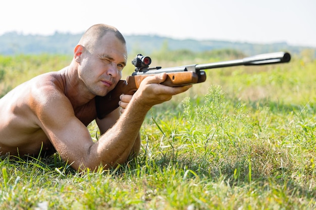 Photo un homme courageux vise avec un fusil en position couchée sur l'herbe