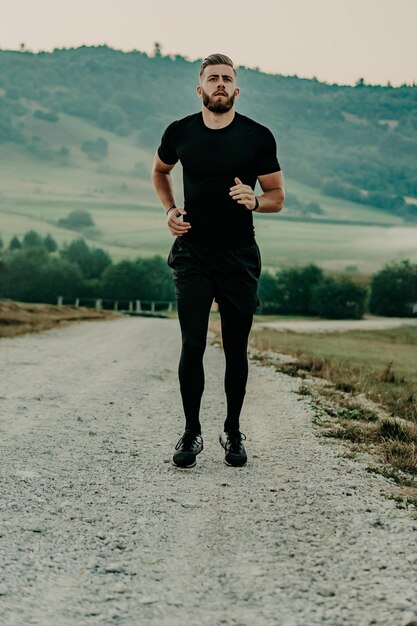 Homme courant / sprintant sur route dans les montagnes. Monter le coureur de fitness masculin pendant l'entraînement en plein air. Jeune homme caucasien.